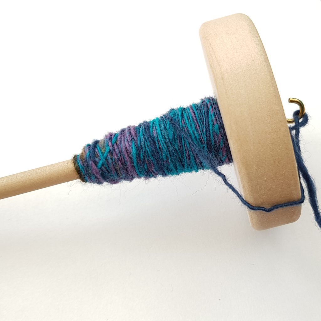 Drop spindle with blue and purple yarn wrapped around